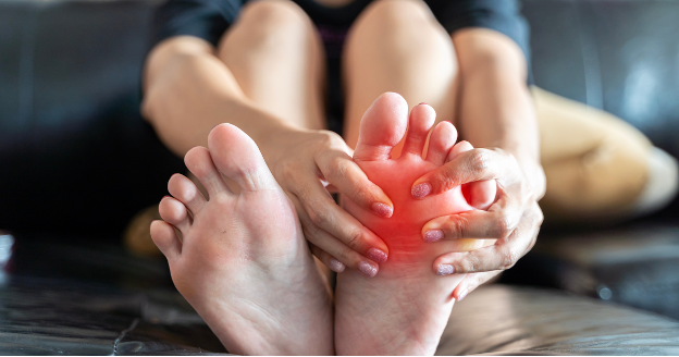 A person holding their foot due to foot pain