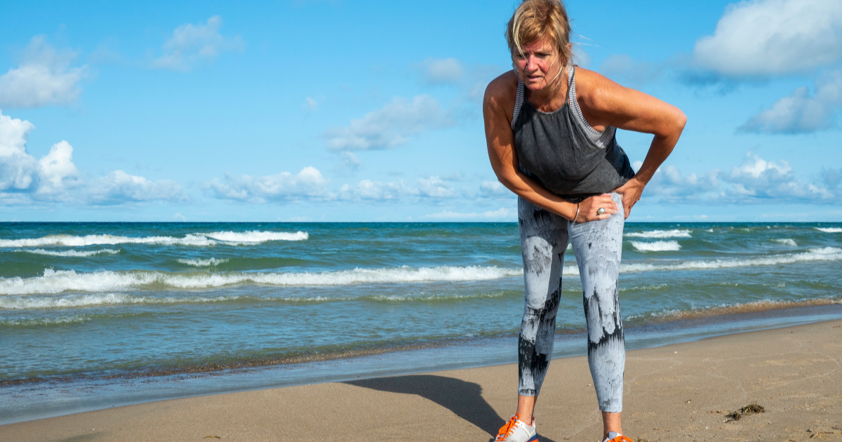 Woman dealing with anterior hip pain while walking on the beach